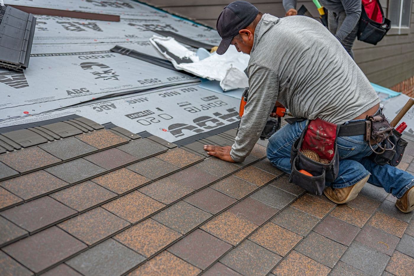 A roofer installing shingles over synthetic underlayment