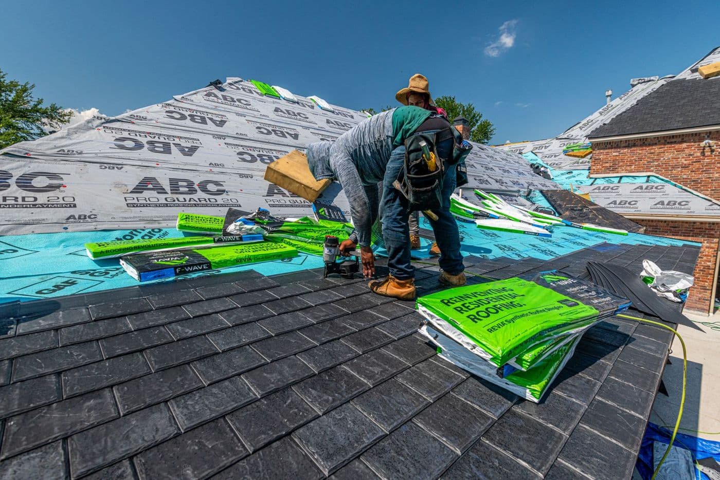 Roofers laying shingles on a brick home